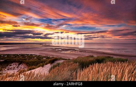 Sonnenuntergang über der Budle Bay mit Blick auf Lindisfarne in der Nähe von Bamburgh, Northumberland, England, Großbritannien Stockfoto