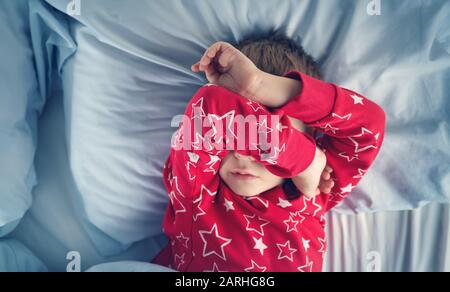 Schlafender Junge im Bett mit blauen Bettungen Stockfoto