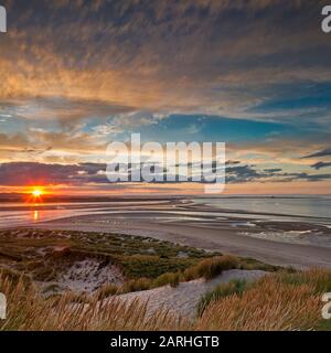 Sonnenuntergang über der Budle Bay mit Blick auf Lindisfarne in der Nähe von Bamburgh, Northumberland, England, Großbritannien Stockfoto