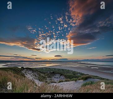 Sonnenuntergang über der Budle Bay mit Blick auf Lindisfarne in der Nähe von Bamburgh, Northumberland, England, Großbritannien Stockfoto