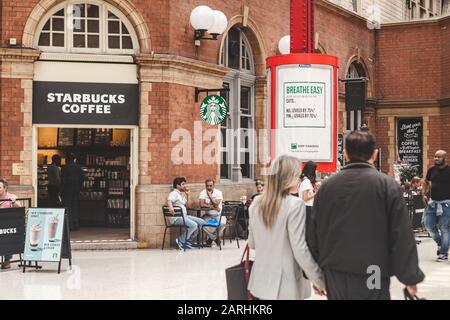 London/Großbritannien - 22/07/2019: Menschen, die ihre Zeit in einem Wohnbereich im Starbucks genießen, das sich innerhalb der Marylebone Station befindet. Der allererste Starbucks Stockfoto