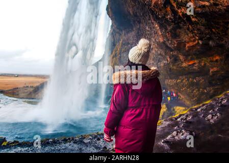 Frau, die auf isländischem Straßenausflug den Blick auf den Wasserfall von Seljalandsfoss in Island genießt Stockfoto