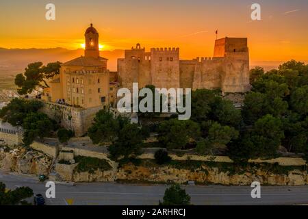 Bei Sonnenuntergang bietet sich ein Panoramablick auf die Burg von Cullera und die beliebte Ferienstadt am Meer in der Nähe von Valencia Stockfoto