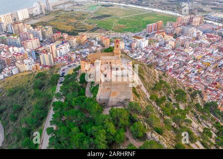 Bei Sonnenuntergang bietet sich ein Panoramablick auf die Burg von Cullera und die beliebte Ferienstadt am Meer in der Nähe von Valencia Stockfoto