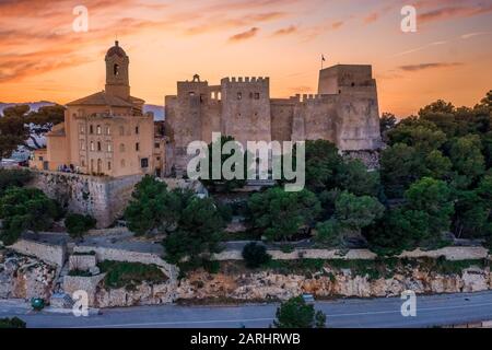 Bei Sonnenuntergang bietet sich ein Panoramablick auf die Burg von Cullera und die beliebte Ferienstadt am Meer in der Nähe von Valencia Stockfoto