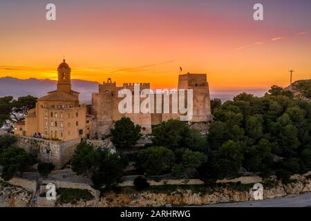 Bei Sonnenuntergang bietet sich ein Panoramablick auf die Burg von Cullera und die beliebte Ferienstadt am Meer in der Nähe von Valencia Stockfoto