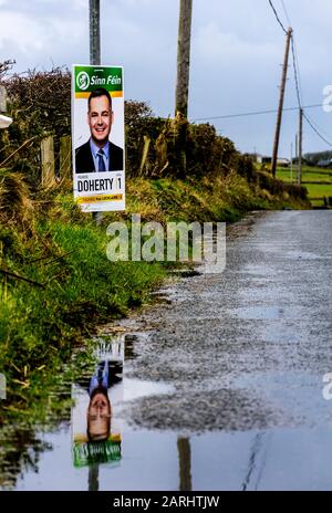 Ardara, County Donegal, Irland. Januar 2020. Ein Wahlplakat für den Kandidaten Pearse Daniel Doherty spiegelt sich in der Pfütze am Straßenrand wider, Doherty ist ein irischer Sinn Féin-Politiker, der seit der Parlamentswahl 2016 Teachta Dála für den Wahlkreis Donegal ist. Die Parlamentswahlen in Irland 2020 werden am Samstag, den 8. Februar 2020 stattfinden. Stockfoto