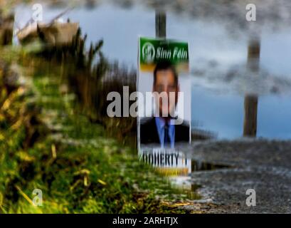 Ardara, County Donegal, Irland. Januar 2020. Ein Wahlplakat für den Kandidaten Pearse Daniel Doherty spiegelt sich in der Pfütze am Straßenrand wider, Doherty ist ein irischer Sinn Féin-Politiker, der seit der Parlamentswahl 2016 Teachta Dála für den Wahlkreis Donegal ist. Die Parlamentswahlen in Irland 2020 werden am Samstag, den 8. Februar 2020 stattfinden. Stockfoto