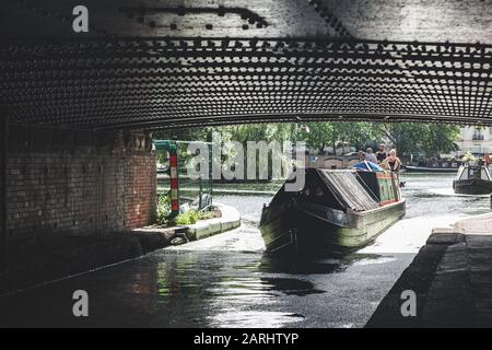 London/UK - 17/07/2019: Zwei Männer, Frauen und ein Hund auf dem Heck eines Schmalboots, das im Regents Canal unter der Warwick Avenue Brücke in Little Venice verläuft Stockfoto