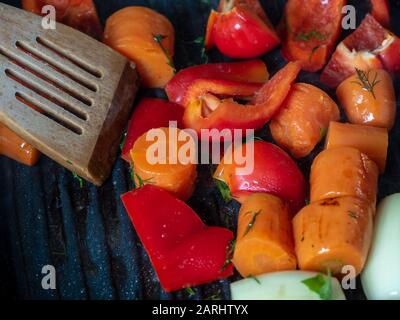 Frisches Gemüse wird in einem Pfannengrill zubereitet. Karotten, süße rote Paprika, Zwiebeln. Konzept vegetarisches und gesundes Essen. Stockfoto