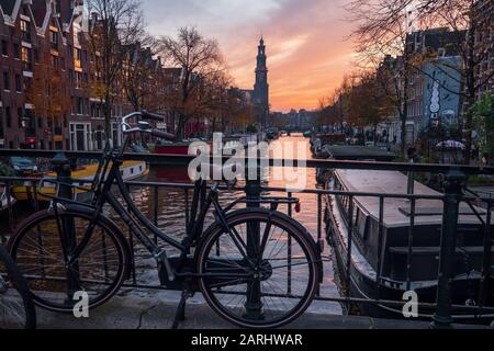 Abend über den schönen Grachten von Amsterdam im späten Herbst. Fahrräder parkten an den Brücken im Vordergrund und booten im Kanal Stockfoto