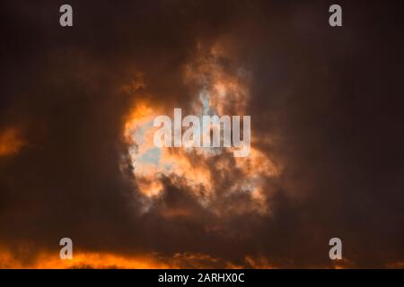 Sonnenuntergang durch abfliegende Sturmwolken, die einen hoffnungsvollen blauen Himmel über dem Kopf zeigen Stockfoto