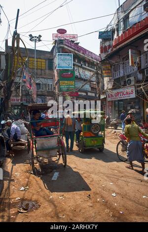 Belebte Straße im Chandni Chowk Gebiet von Delhi, mit Karren, Rickshaws, Tuk Tuk, Motorrädern und Menschen Stockfoto