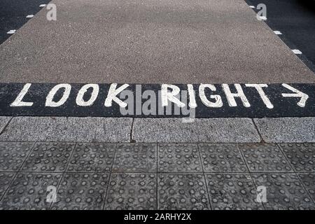 "Look Right"-Straßenmarkierung auf einer Fußgängerüberführung, die Fußgänger daran erinnert, in Großbritannien mit der linken Hand zu fahren. Selektiver Fokus Stockfoto