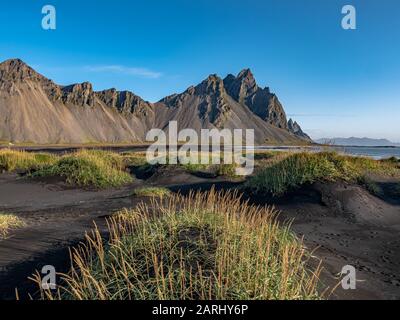 Epischer Luftdronblick an einem sonnigen Tag über die Landschaft des schwarzen Sandstrands in Stokksnes fliegen. Vestrahorn-Berg im Hintergrund. Natur und eg Stockfoto