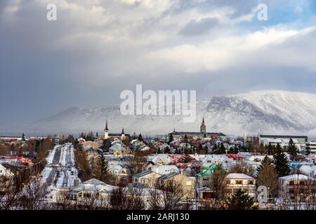 Blick auf Reykjavik vom Hügel mit schneebedeckten Bergen im Winter Stockfoto
