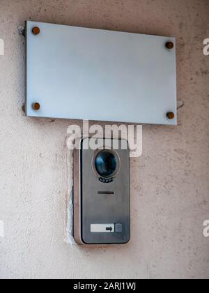 Eine Hinweisschild an der Wand des Gebäudes und eine Anruftaste für das Personal. Weiße rechteckige Platte mit einer Glocke und einer cctv-Gegensprechanlage. Leer für Ihren Text. Mockup Stockfoto