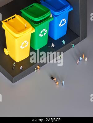 Miniatur-Leute, Arbeiter rund um drei farbcodierte Recycling-Behälter, isometrische Projektion mit Kopierraum. Recycling-Schild an den Behältern, blau, gelb und gr Stockfoto