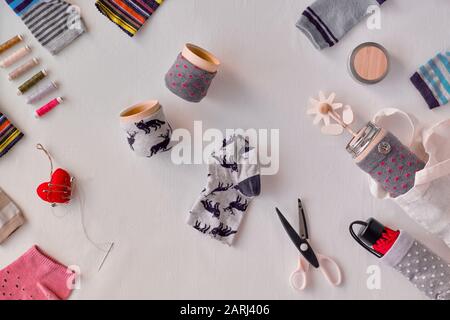 Kein Hausmüll. Bambusbecher und Thermoskannen aus Streusocken machen. Upscale von verwaisten, falsch aufeinander abgestimmten Socken. Flaches Lay, textiler Hintergrund. Stockfoto