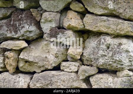 Steinwand aus Schalengestein, leicht mit Moos bedeckt, von Hand gefaltet. Stockfoto