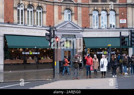 London/Großbritannien - 24. November 2019: Menschen, die am Shake Shack Restaurant am Cambridge Circus in London, Großbritannien, vorbeilaufen. Shake Shack ist ein US-amerikanisches fast Food Stockfoto