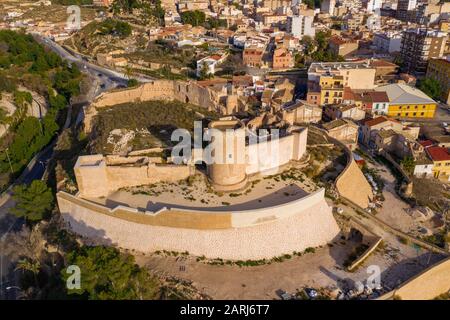 Luftpanorama über der mittelalterlichen Burg Elda mit teilweise restaurierten Mauern, Bergfried und Tor aus weißem Kalkstein in Spanien Stockfoto