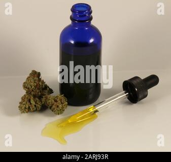 Cbd-Öl in blauer Glasflasche mit Dropper und Blumen Stockfoto