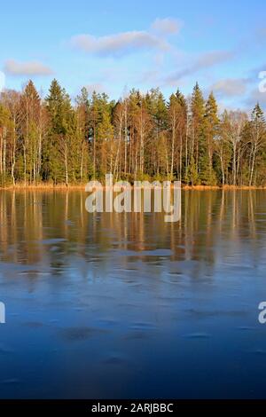Kleiner ländlicher See Sorvasto in Salo, Finnland, an einem sonnigen Wintertag mit strahlend blauem Himmel dünn eisbedeckt. Vertikale Ansicht. Januar 2020. Stockfoto