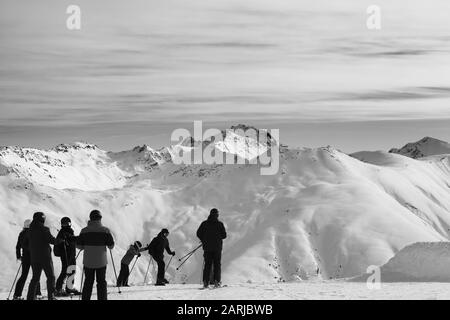 Gruppe von Skifahrern vor dem Start auf der Abfahrt. Hohe Schneeberge und bewölkter Himmel am sonnigen Wintertag. Italienische Alpen. Livigno, Region Lombardei, Stockfoto