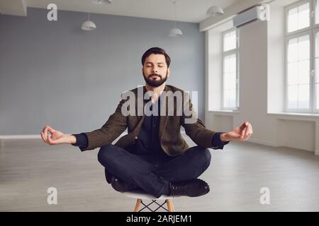 Ruhiger meditativer bärtiger Geschäftsmann entspannt sich auf einem Stuhl im Büro. Stockfoto