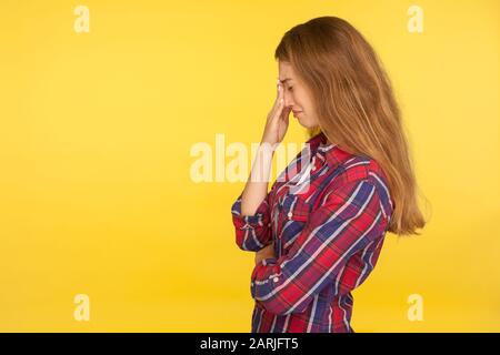 Trauer und Depressionen. Seitenansicht des frustrierten weinenden Ingwermädchens im karierten Hemd, das Tränen wegwischt, sich verzweifelt hilflos fühlt, besorgt um Sondl Stockfoto