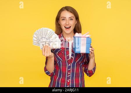 Überraschendes Geschenk, Geldboni. Porträt des staunenden, aufgeregten Ingwermädchens in legeren Hemden mit Schachtel und Dollar, schockiert von Cashback. Stockfoto