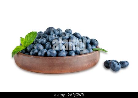 Platte mit Blaubeeren in der Nähe und einem Minzenblatt isoliert auf weißem Hintergrund. Vitaminernährung zur Verbesserung von Sehkraft und Gesundheit. Stockfoto