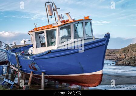 Ein altes, bewaldetes irisches Fischerboot aus dem Wasser auf Blöcken am Hafen Stockfoto