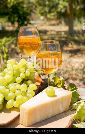 Bernsteinwein in Gläsern auf der Natur: Stillleben mit Käse, Trauben und Wein im rustikalen Stil. Georgischer Nationalwein oder italienischer Wein passito Stockfoto