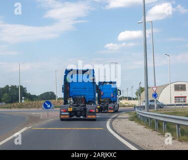 Zwei neue blaue Halb-LKW-Kabine. Große leistungsstarke Traktoren fahren zum Kreisverkehr Stockfoto