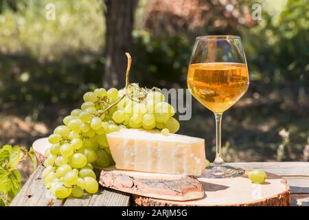 Bernsteinwein in Gläsern auf der Natur: Stillleben mit Käse, Trauben und Wein im rustikalen Stil. Georgischer Nationalwein oder italienischer Wein passito Stockfoto