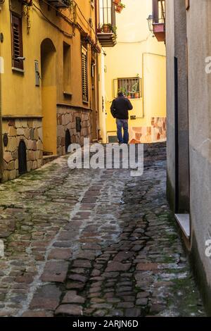 Italien, Sizilien, Provinz Palermo, Pollina. April 2019. Mann, der auf der Kopfsteinpflaster Straße in Pollina spazieren geht. Stockfoto