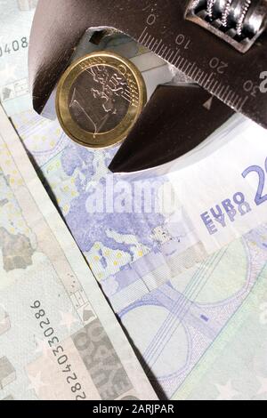 Eine Euro-Münze in einem verstellbaren Schraubenschlüssel auf verschiedenen Euro-Banknoten. Stockfoto
