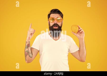 Gesunde orange Rezept Idee. Hipster mit Genius Idee Zeigefinger auf gelben Hintergrund. Bärtiger Mann erhielt glänzende Idee für natürliche Diät. Super Essen Idee. Stockfoto