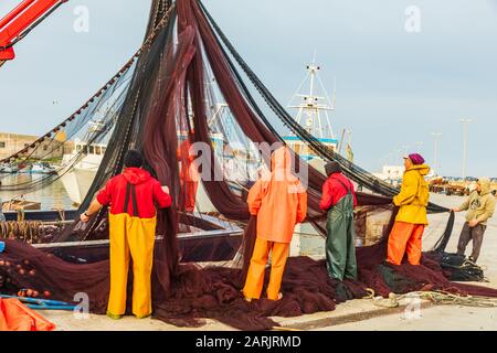 Italien, Sizilien, Provinz Trapani, Trapani. April 2019. Fischer sammeln Fischernetze an den Docks des Hafengeländes in Trapani. Stockfoto