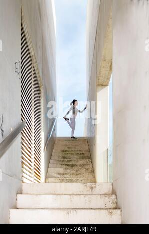 Fit Woman, die warm-up-Beinstreck macht, draußen in einer modernen urbanen Umgebung Stockfoto
