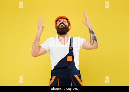 Endlich. Entwicklung der Umgebung. Schutzhelm. Verbesserung und Renovierung. Brutaler Bauherr. Bärtiger Kerlarbeiter auf gelbem Hintergrund. Uniform des Ingenieurbauers. Heimdekor. Fühlen Sie sich erleichtert. Stockfoto