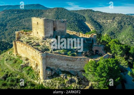 Luftaufnahme der spanischen Burg Jalance auf einem Hügel aus dem 12. Jahrhundert, bestehend aus einem inneren Burghof, unregelmäßige Außenmauer mit Rundturm Stockfoto