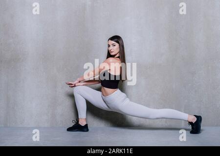 Fitnessfrau, die Ausfallübungen für das Training des Muskeltrainings am Bein macht. Aktives Mädchen, das eine Ausfallübung mit einem Beinschritt nach vorne macht. Stockfoto