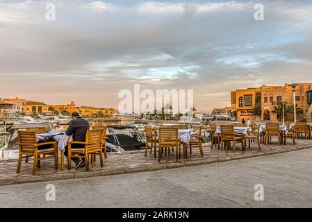 Restaurant mit einem Mann, der bei Sonnenuntergang an einem Tisch in der Abu tig Marina in el Gouna, Ägypten, 12. Januar 2020 sitzt Stockfoto