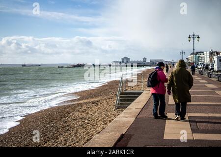 Ein Paar Frauen mittleren Alters, die im Winter am Strand in Southsea, Hampshire spazieren gehen Stockfoto