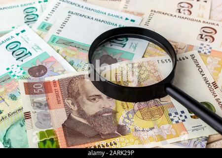 Lupe auf bulgarischen Lev Banknoten. Überprüfen Sie die Echtheit des Geldes. Geldkonzept für Wohlstand, Armut und Fälschung. Vorderansicht. Stockfoto