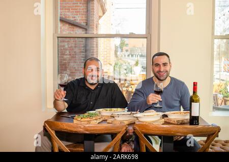 Zwei stolze Unternehmer sitzen zusammen an einem Restauranttisch mit Wein Stockfoto