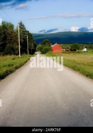 Unbefestigte Landstraße des ländlichen Vermont mit roter Scheune im Unmut Stockfoto